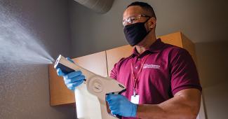 Employee using an electrostatic spraying system to perform an all surface cleaning