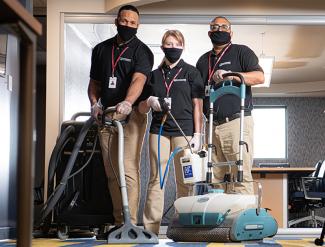 Professional carpet cleaning company wearing masks and disinfecting an office