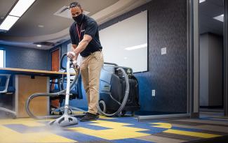 Man steam cleaning carpet wearing mask