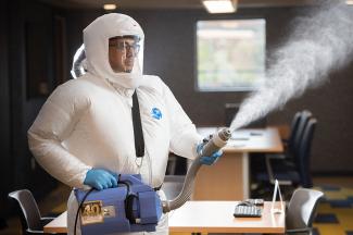 Man in protective suit using fogger.