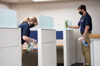 Cleaners with protective gear wiping work surfaces.