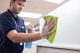 Janitronics cleaning technician cleaning cubicle partition with yellow microfiber cloth