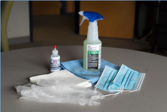 a Janitronics desk kit, including face mask, gloves, hand sanitizer, a spray bottle of sanitizer, and microfiber cloth