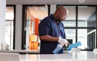 Janitronics employee spraying blue towel over counter