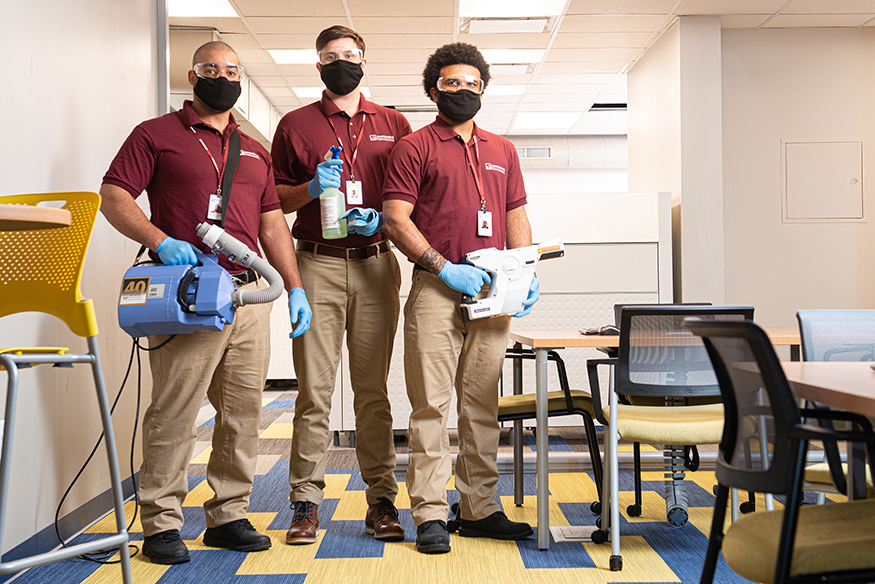 three Janitronics cleaning technicians with different cleaning products