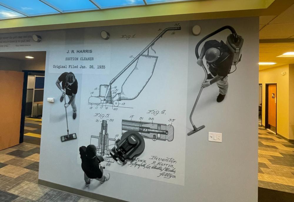 a photo of the mural in Janitronics' Albany offices, which includes diagrams from the 1935 suction cleaner patent by John R Harris