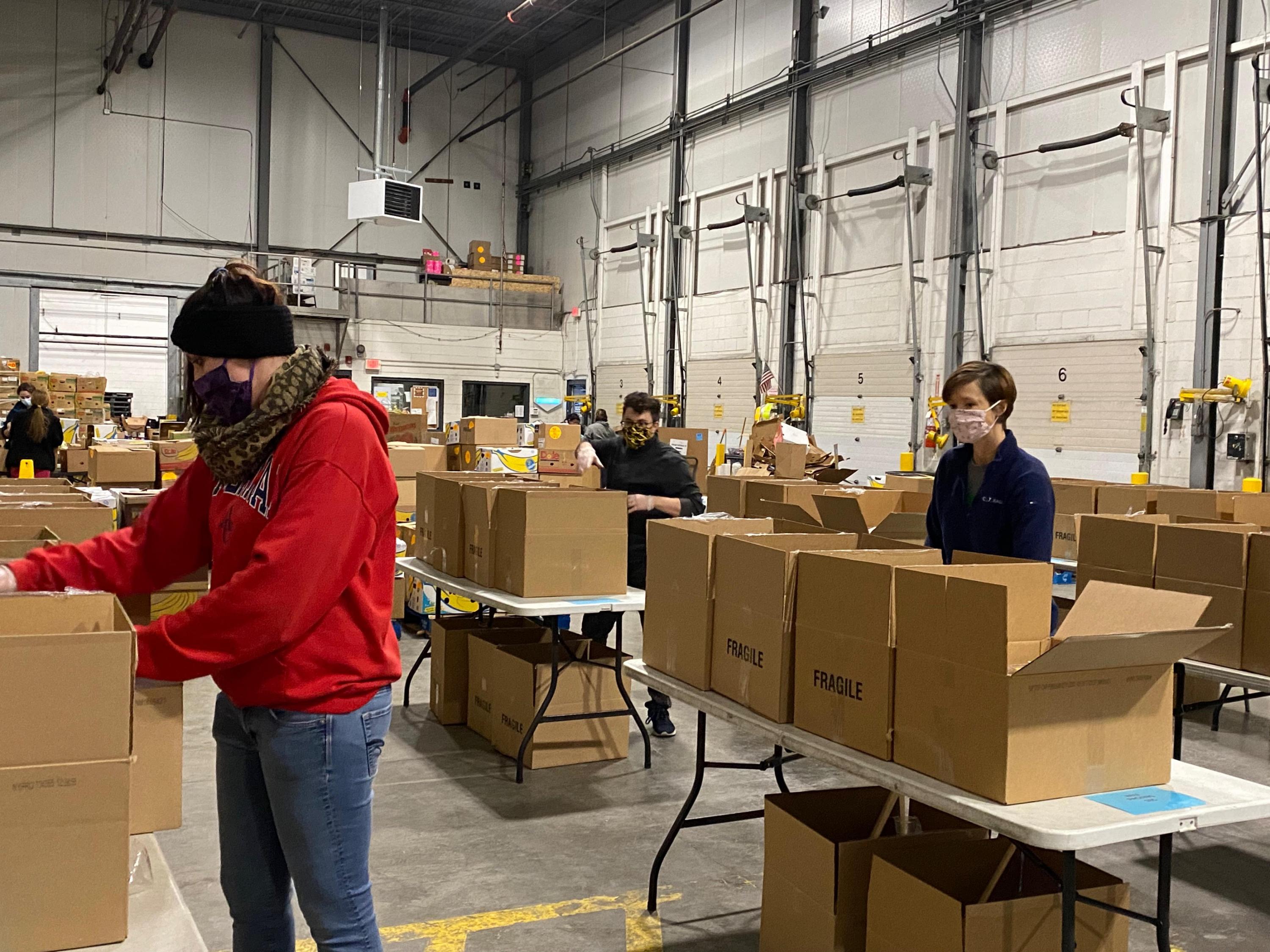 Janitronics team members volunteering at the regional food bank packing boxes with food