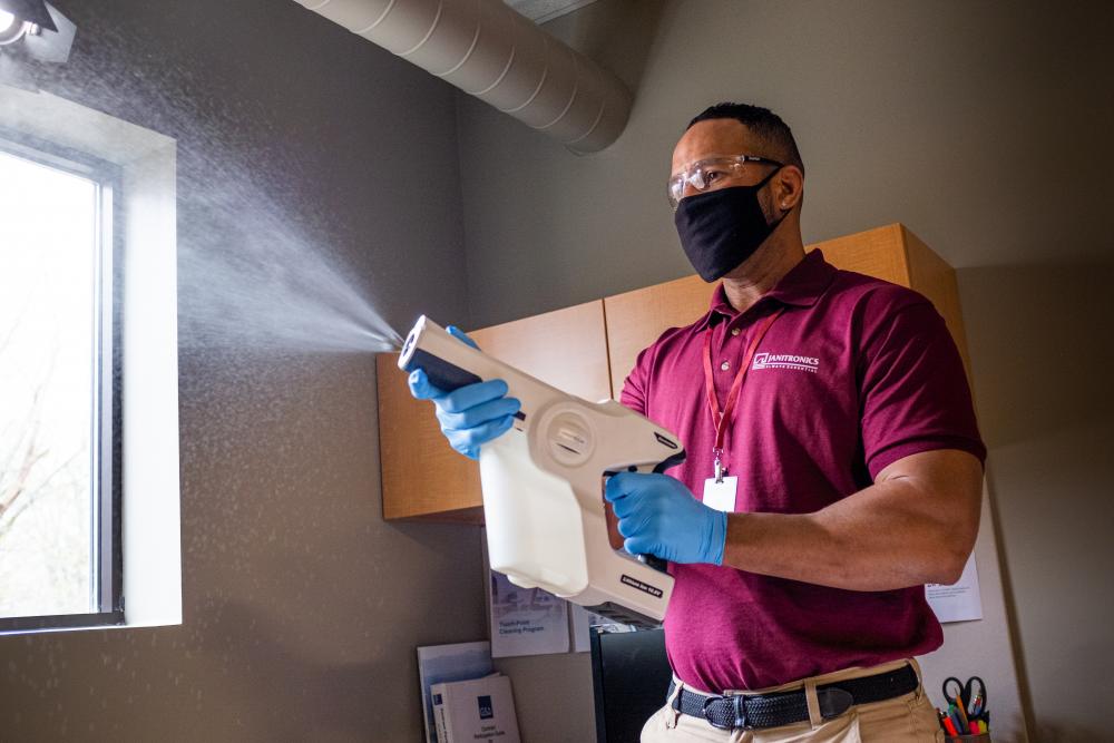 Janitronics cleaning technician cleaning office with electrostatic sprayer
