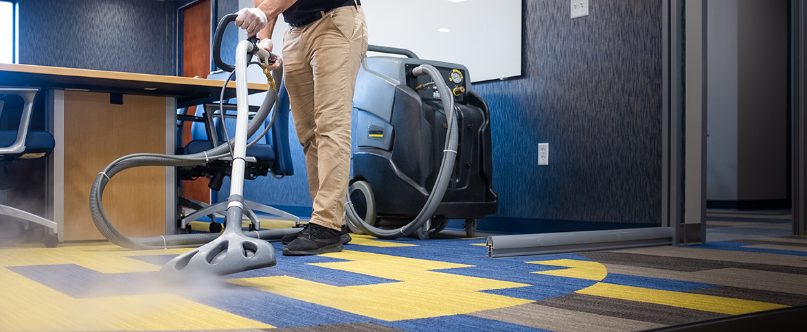 Janitronics employee steam cleaning office carpet