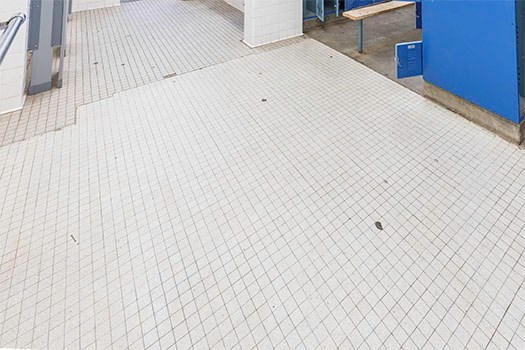 floor in a locker room before SaniGLAZE treatment