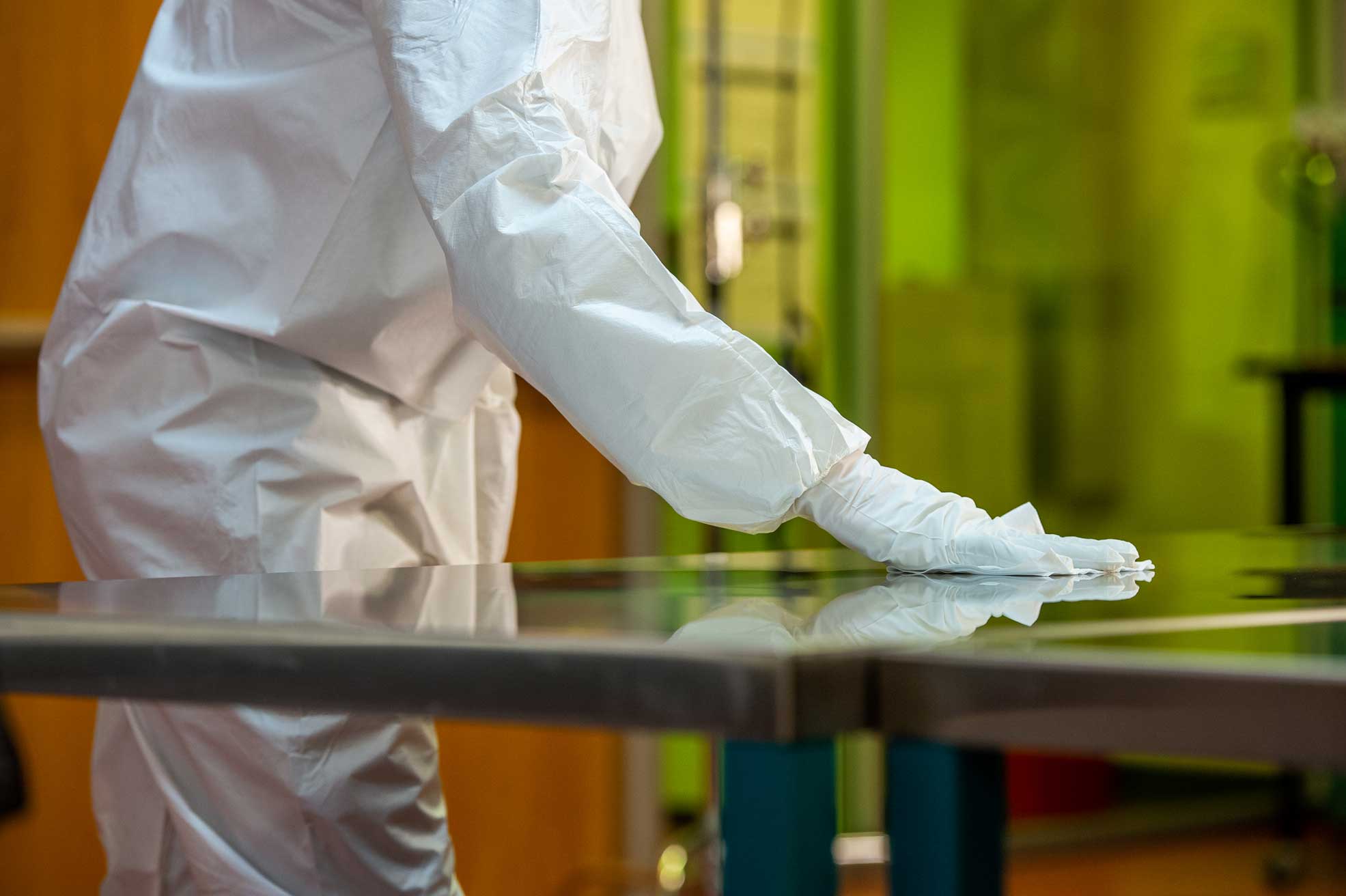 A person in a protective suit wiping a counter.