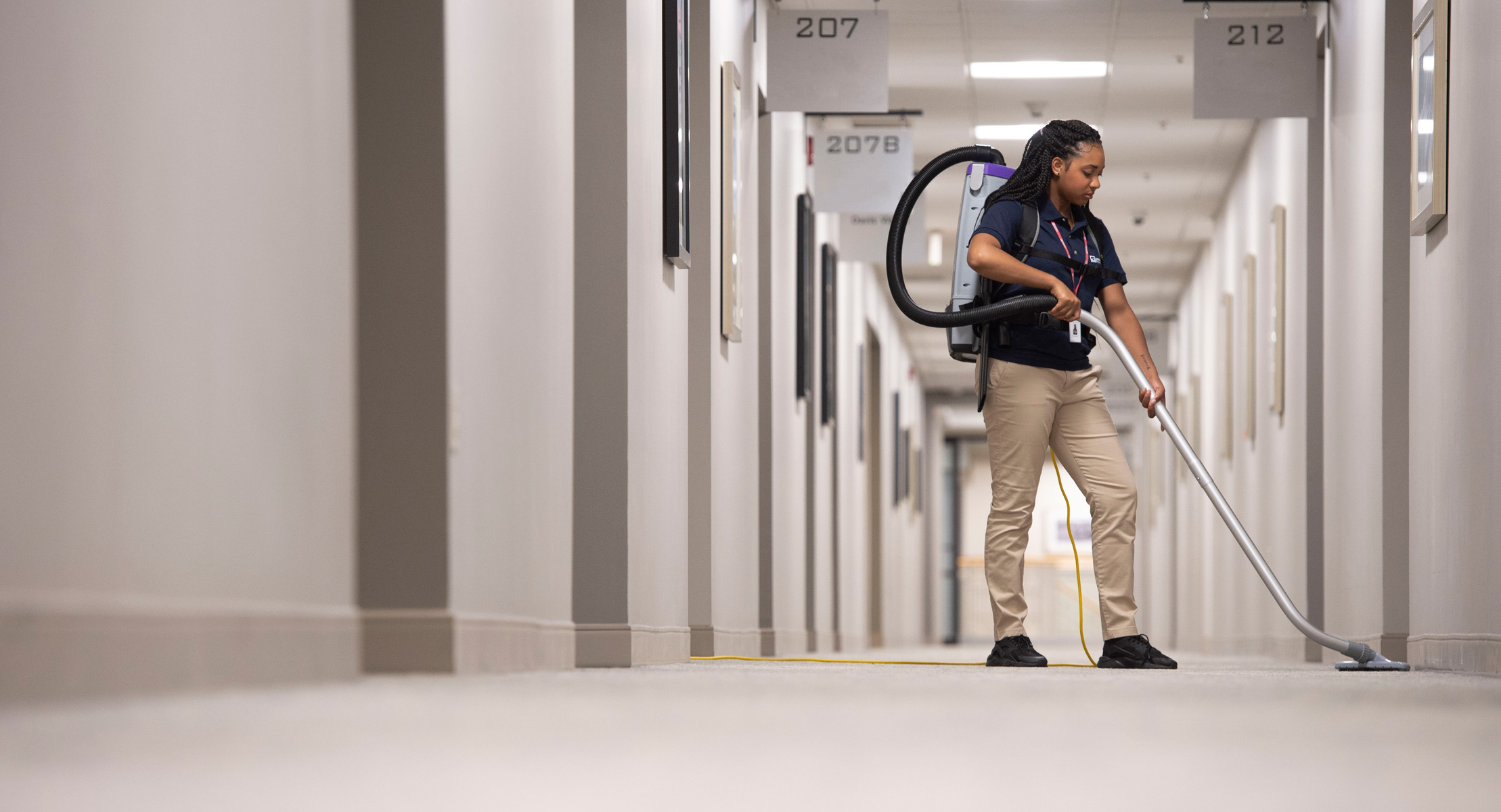 Janitronics employee with backpack vacuum in medical hallway